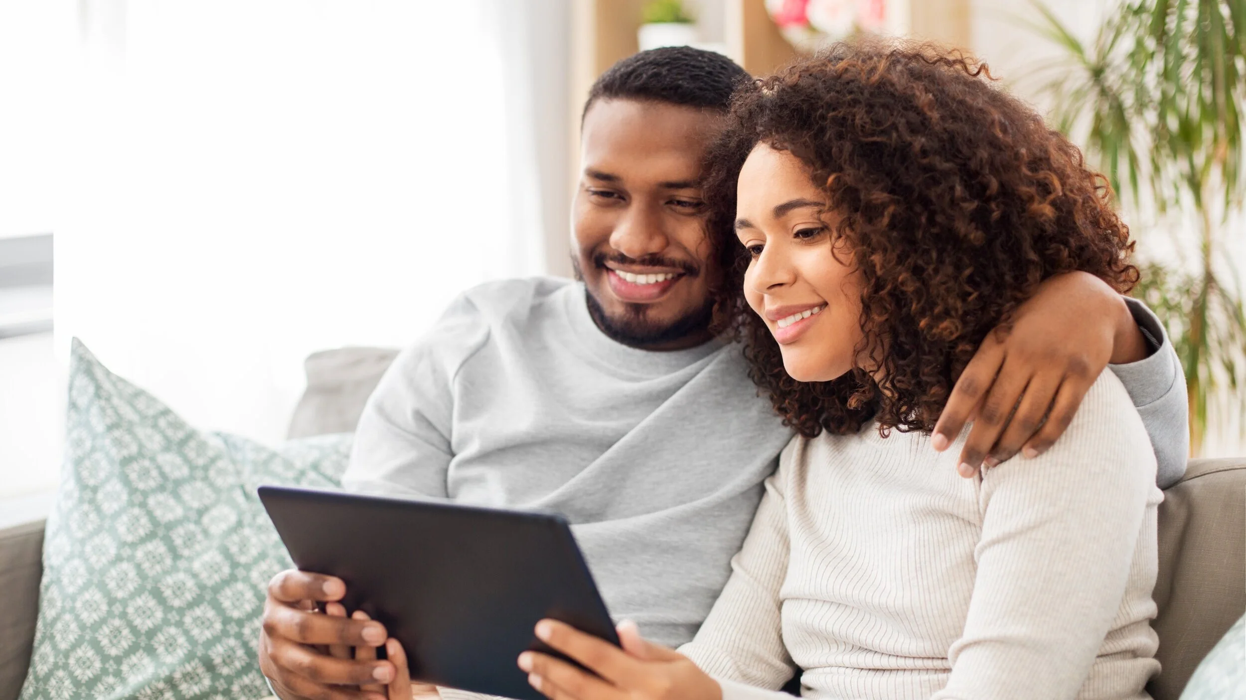 A couple smiling together while looking at a tablet
